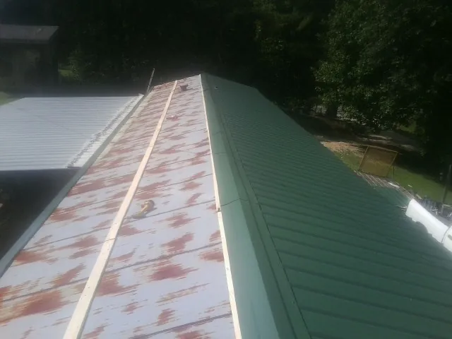 Old rusted panels beside newly installed green metal roofing — Wind Damage Roof Repair by Roofing Brothers in Sherrill